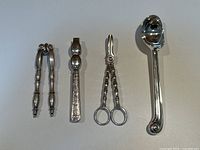 Four silver plated serving utensils arranged side by side