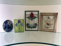 Five stained glass window pieces including oval, rectangular floral panels, rosebud window piece, and framed bird panel