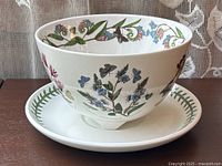 Full view of berry bowl and matching plate showing botanical and butterfly illustrations on both pieces.