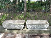 Two rectangular concrete planters side by side outdoors on stone ledge