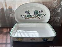 Photo showing the oval dish with botanical floral design in the background and rectangular dish with fruit and flower pattern in the foreground.