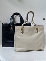 Both black and cream leather handbags side by side showing overall shape and size