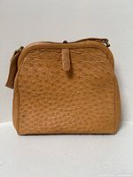 Front view of the caramel ostrich handbag showing the texture and overall shape.