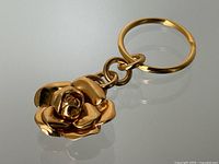 Full view of gold-tone metal Chanel keychain with Camellia charm and key ring