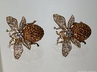 Pair of gold-tone bee-shaped clip-on earrings on white background
