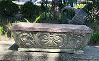 Front and side view of weathered vintage rectangular concrete planter with ornate scroll design.