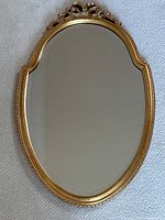 Full view of vintage gilt oval wall mirror laid flat, showing overall shape and detail.