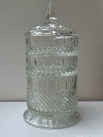 Front and side view of vintage Indiana Glass three tier stacking candy dish with lid, showing clear diamond patterned glass and pointed finial on lid.