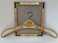 Full view of wooden clothes hanger laid over the picture frame showing size and colors