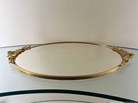 Full front view showing round mirror surface, gilt metal frame and floral ormolu handles.