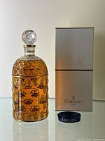 Perfume bottle, box, and ribbon arranged on reflective surface.