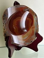 Top view of polished natural agate geode dish on wooden stand showing banded color patterns and glossy finish.