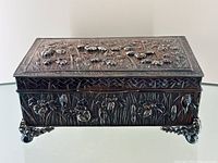 Rectangular jewelry box top and front view showing embossed floral pattern on lid and sides with ornate claw feet