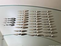 Overview of all 34 holders arranged on glass surface showing four handle styles
