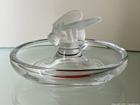 Front view of clear circular dish with frosted bee figurine perched on rim