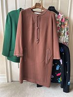 Overview of six garments on hangers: brown dress front, green blazer left, floral blazer right, black cardigan visible.