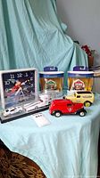 Wide view of all lot items including Disney clock, diecast vehicles, and collectible boxes on blue fabric background.