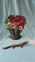 Full view of cast iron fruit basket door stop and brass alligator nutcracker on blue fabric background.