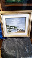 Framed 8x10 coastal scene painting with boats and houses, signed, showing full art and frame.