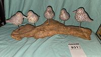 Full frontal view of the six abstract handcarved birds mounted on natural driftwood base with visible wood grain and metal rods supporting the birds.