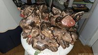Top view of a carved wooden sculpture featuring multiple pigs with painted red noses and carved details.