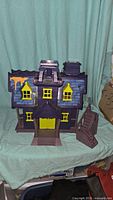 Front view of the Scooby Doo haunted mansion playset showing purple exterior with yellow windows and door.