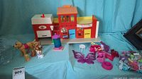 Overview of the Fisher-Price Play Village toy set with toy dogs and play accessories arranged in front of a blue background.