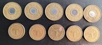Top row: five New York City Transit Authority subway tokens featuring a circular center and raised edge text. Bottom row: five Massachusetts Bay Transportation Authority (MBTA) tokens with a 'T' emblem in the center and inscription around the edge.