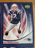 Close-up image of Tom Brady card from 2006 Upper Deck Boston Globe set showing player in Patriots uniform holding a football.