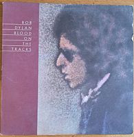 Front cover of Bob Dylan's Blood on the Tracks vinyl album with a profile image of Bob Dylan against a purple background showing wear on corners and edges.