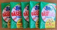 Five unopened Topps 1990 Major League Baseball wax packs in original colorful packaging displaying Topps logo and promotional details