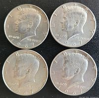 Obverse side of four 1967 Kennedy half dollar silver coins showing the profile of John F. Kennedy.