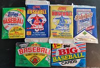 Photo showing six unopened baseball card wax packs from various brands and years (1987 Topps, 1988 Topps Big Baseball, 1989 Bowman, 1989 Score, 1990 Score, 1991 Upper Deck). The colorful packaging and logos are clear and legible.