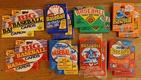 Photo of sixteen unopened wax packs of baseball cards from 1988 and 1989 arranged on wood surface.