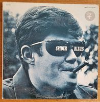 Front cover of the vinyl album Spider Blues featuring a black-and-white image of Spider John Koerner with cigar and sunglasses reflecting the album name.