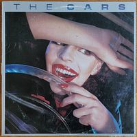Front cover of The Cars 1978 debut album featuring woman smiling behind steering wheel.