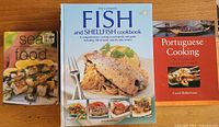 Photo showing the three cookbooks in the lot: 'Sea Food' by Kay Scarlett, 'The Ultimate Fish and Shellfish Cookbook' by Kate Whiteman, and 'Portuguese Cooking' by Carol Robertson.