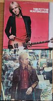 Front covers of two Tom Petty and the Heartbreakers vinyl albums: 'Damn the Torpedoes' with Tom Petty holding guitar, and 'Hard Promises' with Tom Petty in leather jacket.