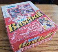 Sealed unopened box of Donruss 1990 Baseball Cards, showing original plastic wrap and branded tape, red and white box with player images and text.