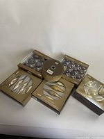 Overview of five boxed sets of Martha Stewart Christmas decorations including purple and gold baubles, gold wired ribbon and glass ornaments.