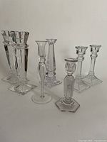 Seven candlesticks on white background showing variety of shapes and clear material.