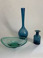 Full set of three teal glass pieces: tall vase, small vessel, and freeform bowl, displayed on neutral background.