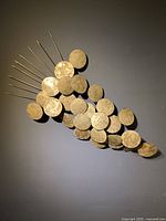 Full view of handcrafted metal grape cluster wall sculpture mounted on dark wall showing overall shape and size.