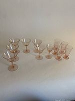 Full lot showing all 13 pink depression glass stems arranged in rows by size and style.
