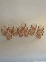 All 13 pink Depression glass items arranged grouped by type on a white background.