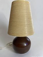 Front view of lamp showing spherical dark brown base and cream woven shade