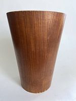 Full front view of the wooden wastebasket showing the tapered shape and wood grain finish.