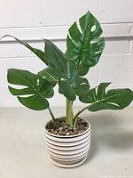 Full view of artificial philodendron plant with 8 green leaves and decorative white pot with horizontal stripes.