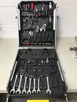 Opened aluminum tool box showing placement of various hand tools inside foam trays.