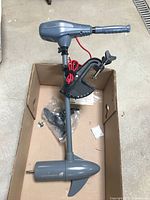 Full view of the assembled Newport Vessels electric trolling motor in gray color, mounted clamp visible on lower shaft, red power cables coiled on shaft.